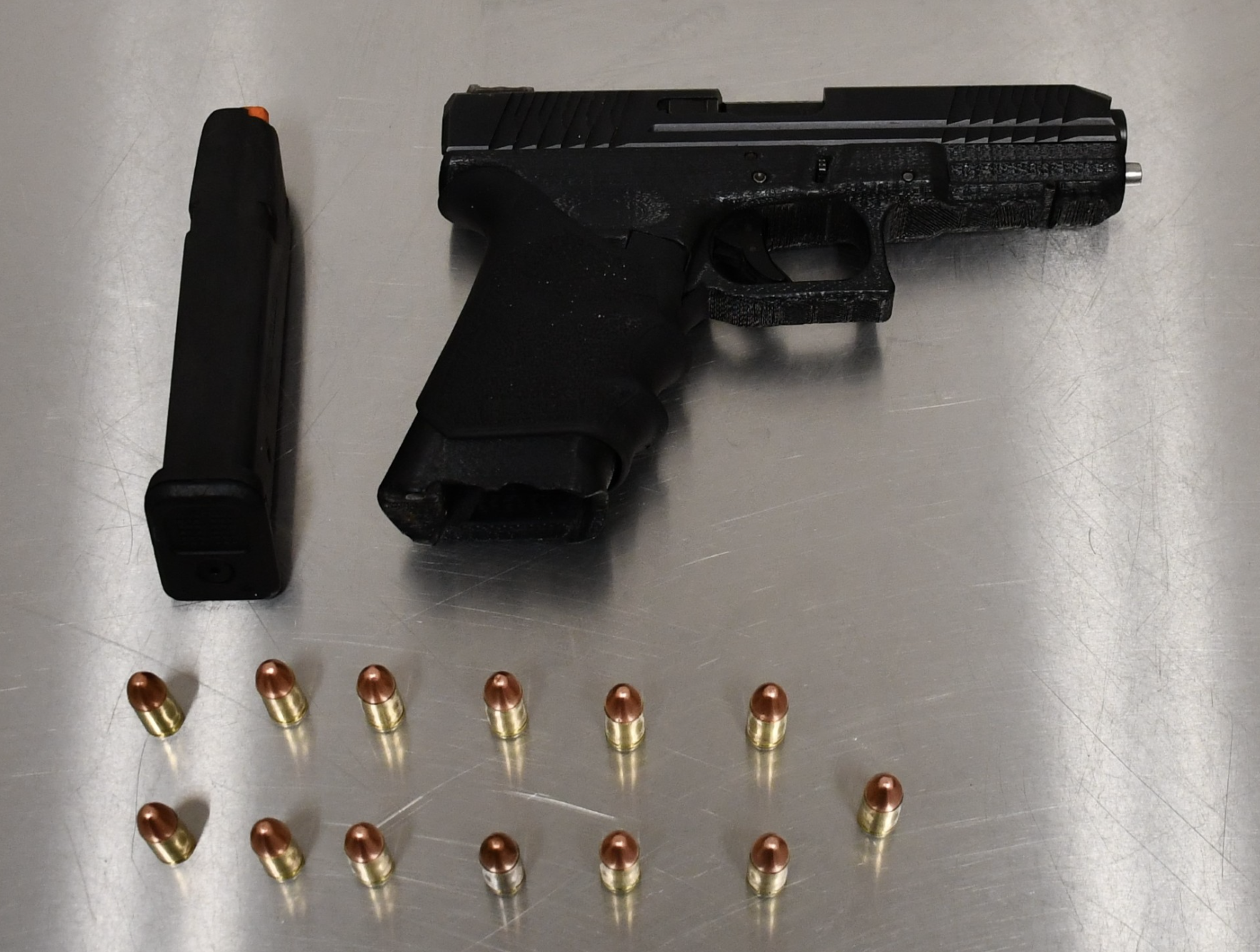 A suspected 3D printed handgun and some bullets on a steel table.